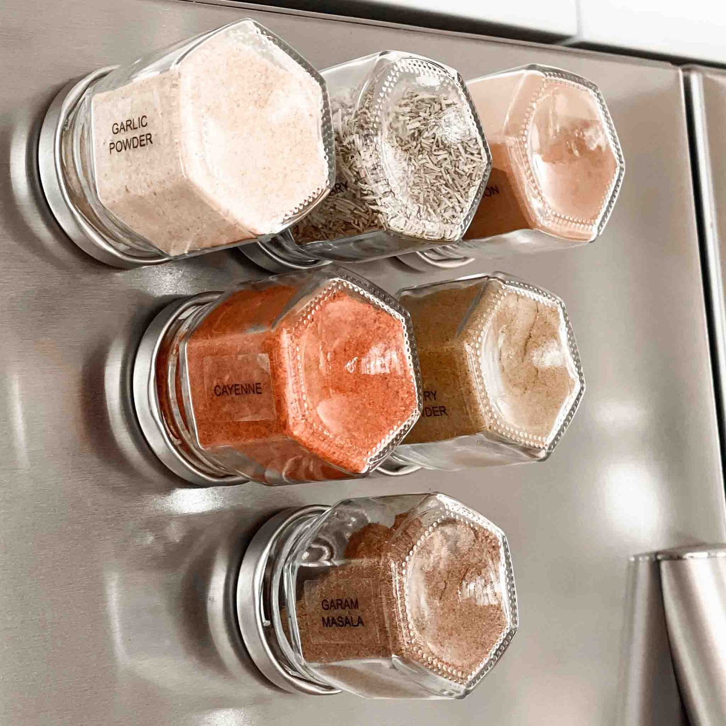 A close up picture of magnetic spice jars on a silver fridge